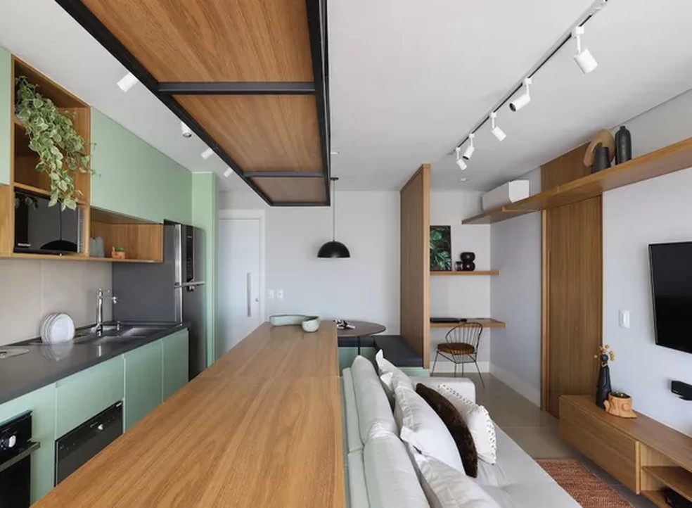 Na cozinha integrada assinada pelo escritório Lilutz Arquitetura, os armários coloridos compõem perfeitamente com a planta pendente disposta em um dos nichos — Foto: Mariana Orsi / Divulgação