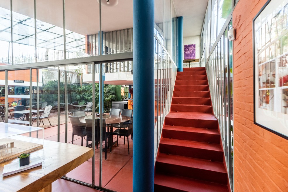 A escada interna com laterais de vidro leva a um mezanino com ampla vista do entorno verde — Foto: Refúgios Urbanos / Rafa D’Andrea / Divulgação