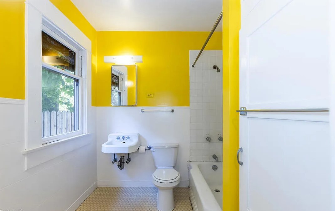 Um dos banheiros da casa tem cor amarela e possui banheira