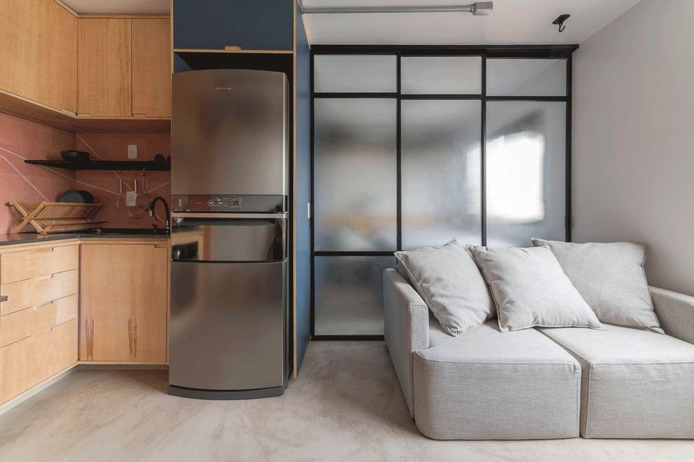 Para o apê de 26 m², o escritório COTA760 Arquitetura desenhou um armário azul que camufla a porta do banheiro e embute a geladeira — Foto: Cris Farhat / Divulgação