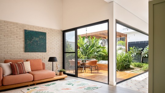 Casa minimalista tem pontos de cor e integração com jardim e piscina