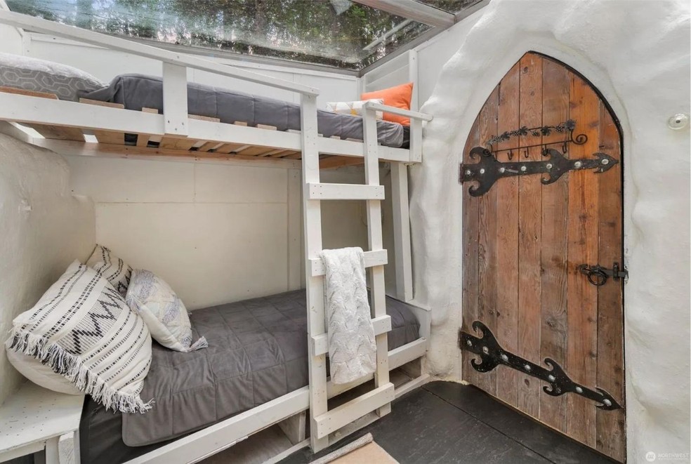 Um dos quartos tem porta de madeira estilo castelo e uma cama beliche — Foto: North West / Reprodução