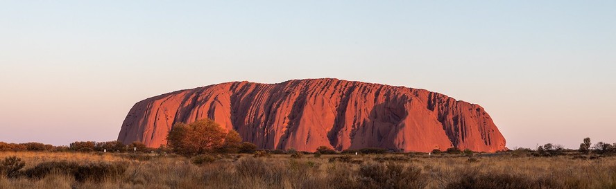 Uluru é uma rocha enorme localizada na paisagem plana da Austrália central. É considerado um local sagrado para o povo aborígene Anangu