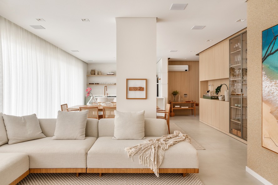 LIVING | A base branca do apartamento ganha a companhia da madeira clara dos painéis das paredes. Sofá Nube, da Studio Ambientes. Ao fundo, o carrinho assinado por Linda Martins, fornecido pela mesma marca do sofá, confere apoio na entrada do imóvel