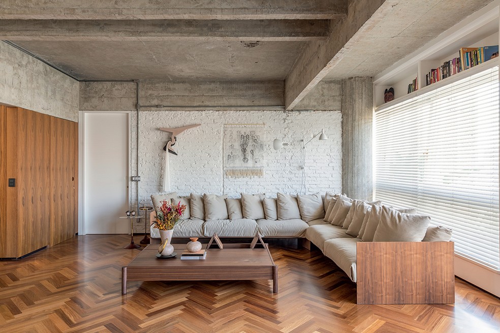 Na sala de estar, o sofá em formato de L otimiza espaço para as festas da moradora. Projeto do escritório Bloco Arquitetos, com colaboração do Casulo Arquitetura — Foto: Maíra Acayaba / Divulgação