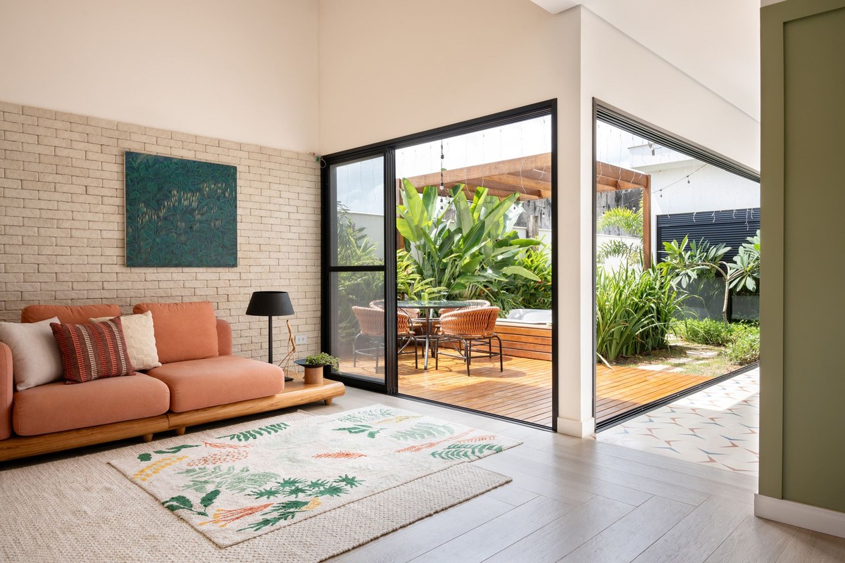 Casa minimalista tem pontos de cor e integração com jardim e piscina