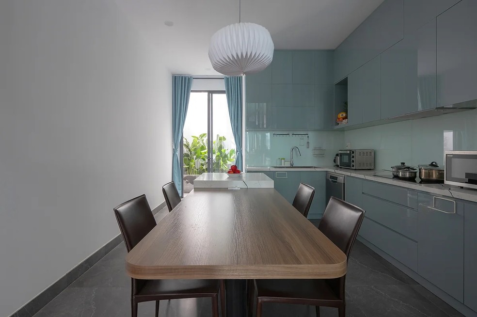 A decoração da cozinha é marcada pela marcenaria azul-esverdeada — Foto: Triệu Chiến / STD Design Studio / Reprodução