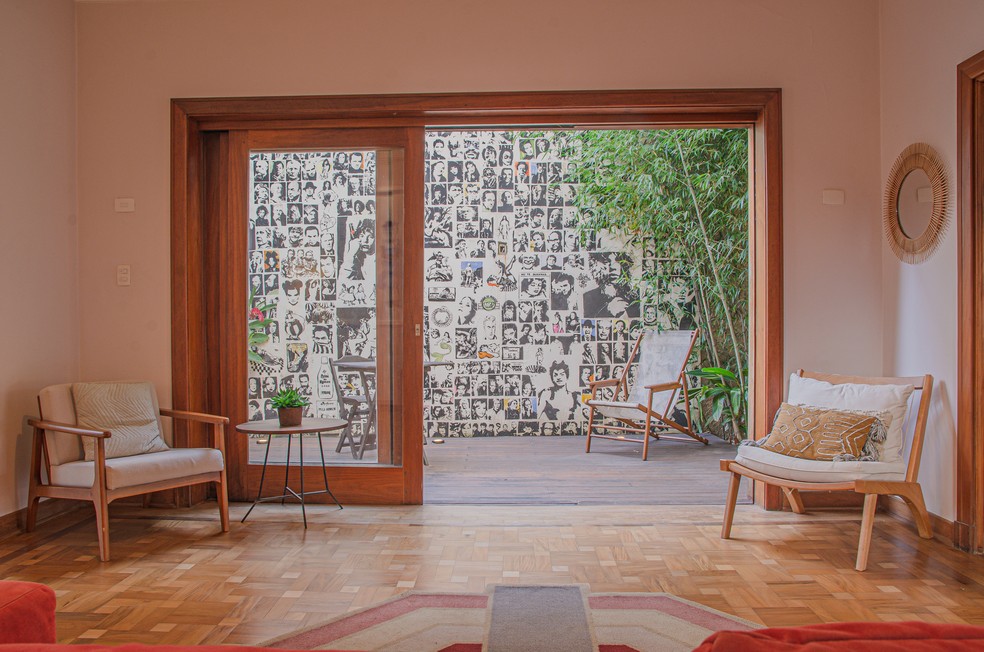 SALA | Na sala, de frente ao sofá vermelho, uma porta de vidro se abre para a área externa da casa — Foto: Lari Kennynsc / Divulgação