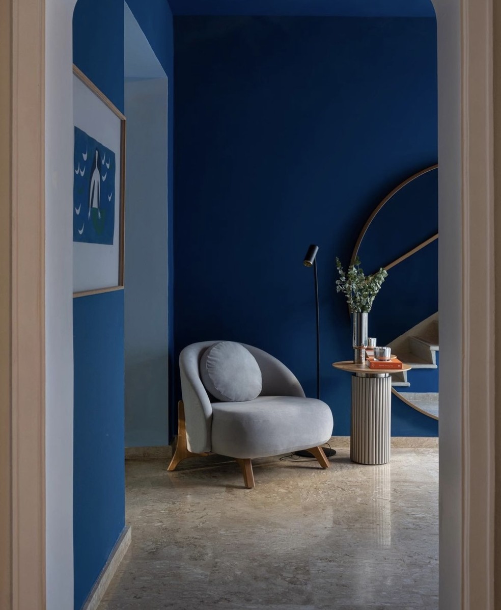 Neste hall de entrada, as paredes e o teto foram pintados de azul escuro — Foto: Cacá Bratke / Divulgação