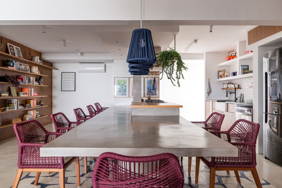 A mesa de concreto está ligada à bancada da cozinha, criando um amplo espaço de convivência — Foto: Rafael Renzo / Divulgação