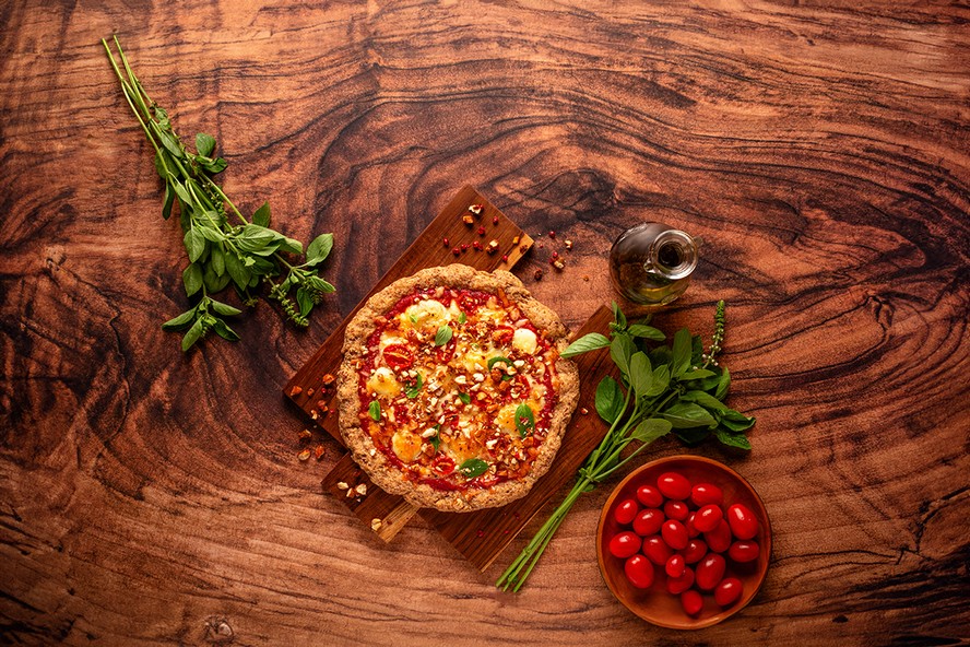 Receita de pizza low carb com queijo minas, muçarela de búfala e tomates pode ser finalizada com manjericão e bacon vegetal