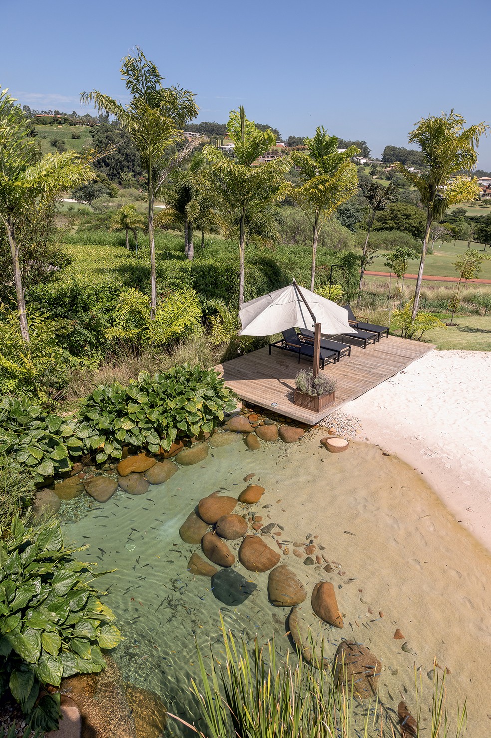 Casa ganha vasto jardim com lago artificial, piscina e quadra de areia