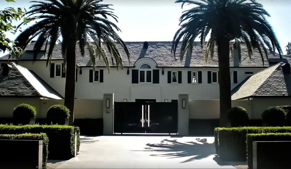 Ao lado dos portões da mansão, duas palmeiras altas chamam a atenção — Foto: Robb Report / Instagram / Reprodução