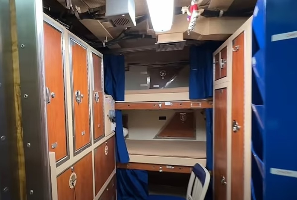 Uma das cabines do barco com beliche triplo e espaço de armazenamento de objetos pessoais — Foto: YouTube / Barefoot Vlogger / Reprodução
