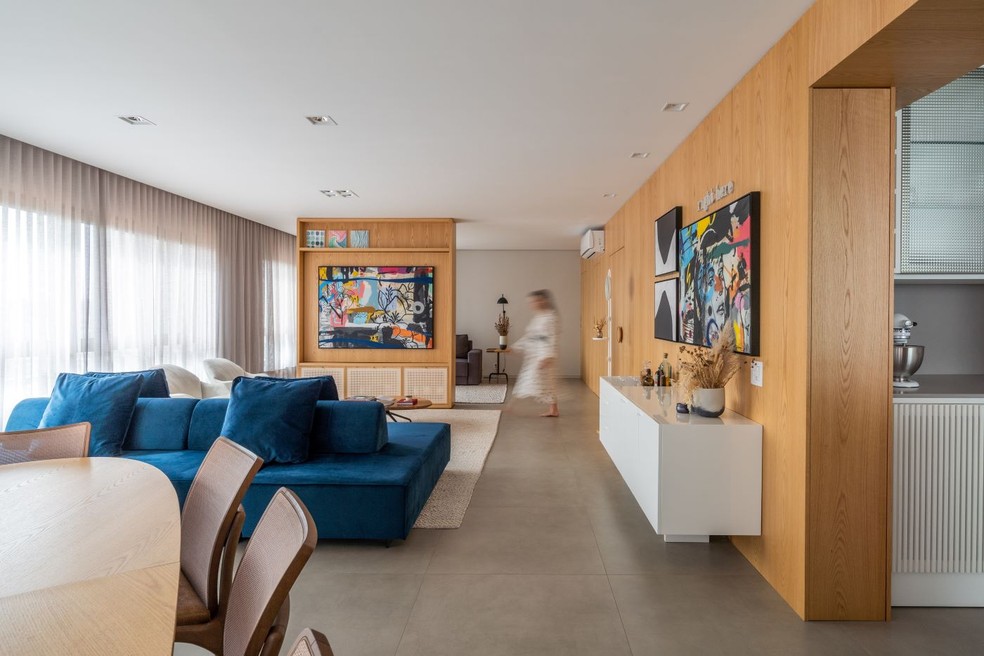 Os ambientes integrados, com uma divisória rotacional, têm sofá de veludo azul desenhado pelo escritório  TWB Arquitetura — Foto: Vinícius Ferzeli/Divulgação | Projeto do Studio TWB Arquitetura