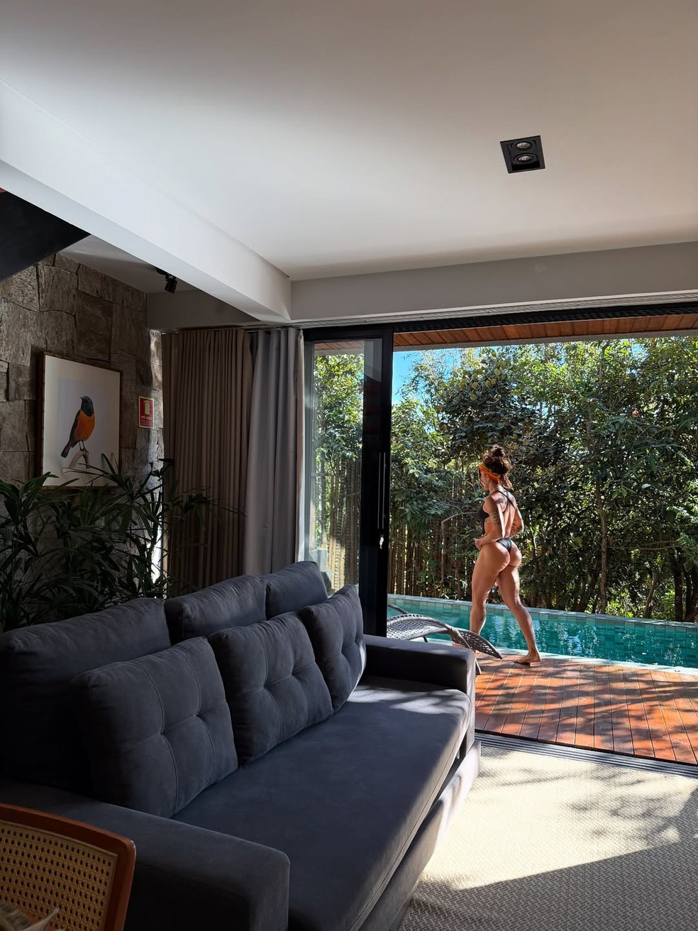 A sala de estar tem um sofá espaçoso e portas que se abrem para a área externa — Foto: Instagram/Reprodução