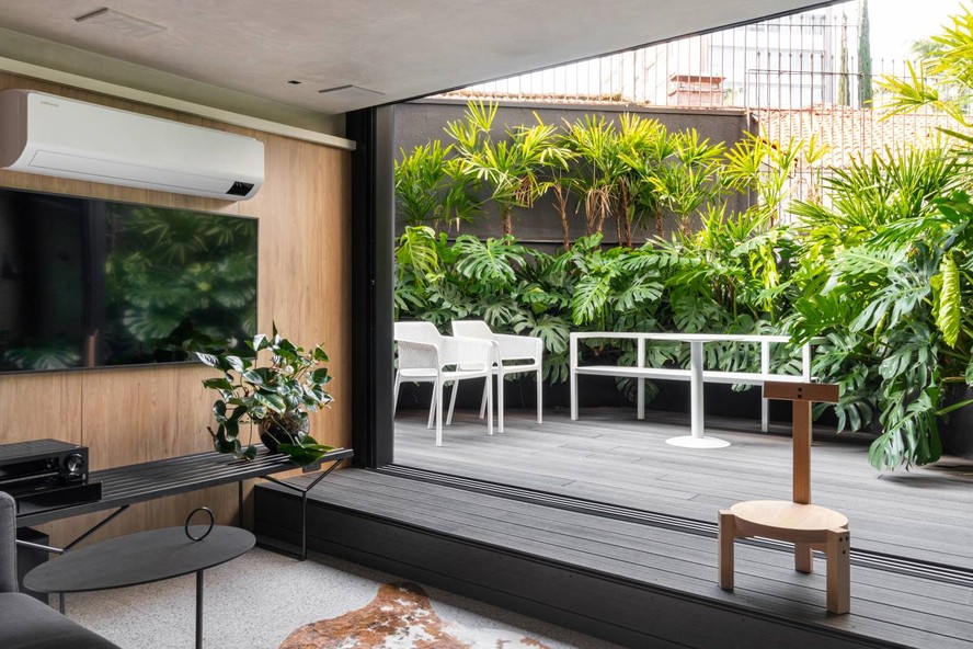 CONEXÃO | O jardim se conecta com a área social, que tem banco Bertoia, produzido pela Artesian, como rack para TV. Cadeira Bordadeira Girafa da Marcenaria Baraúna