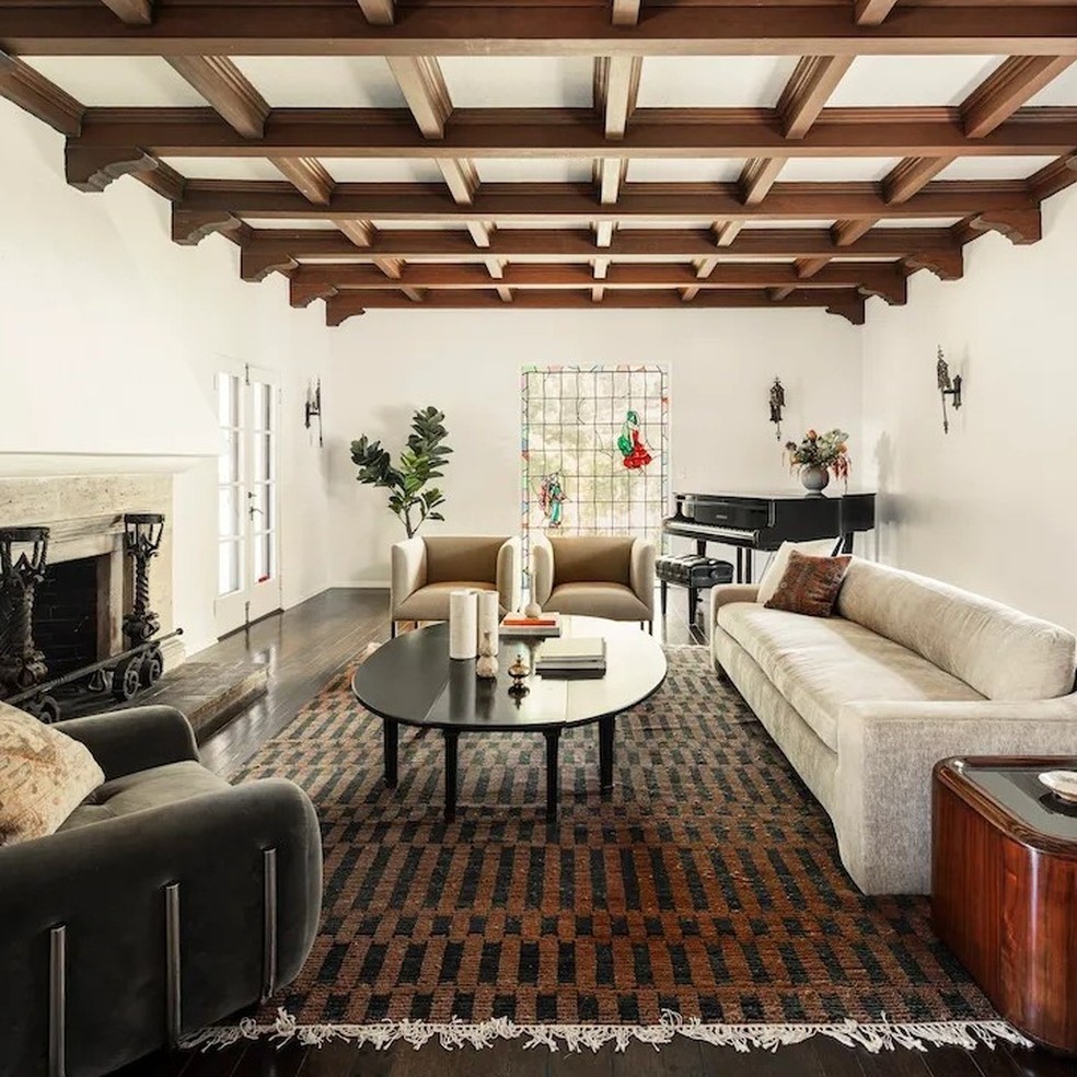 A sala de estar tem lareira, um sofá grande branco e até um piano — Foto: Robb Report / Instagram / Reprodução