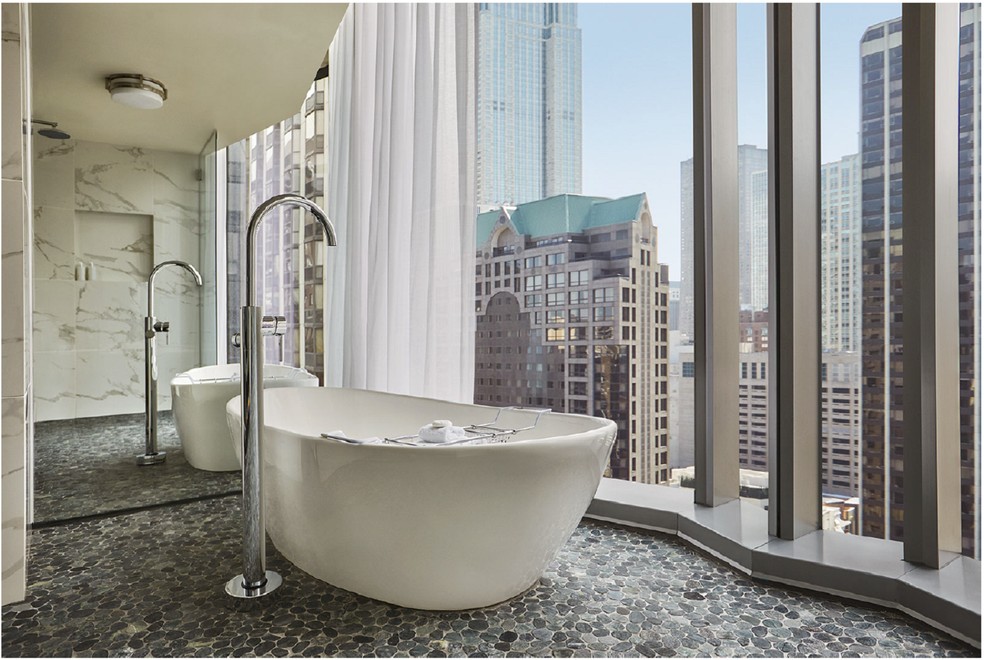 O banheiro da suíte Junior, com piso de pedras, também tem vista para os prédios da cidade — Foto: Viceroy Chicago / Divulgação
