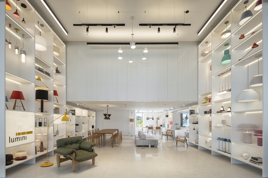 Os profissionais do BLOCO Arquitetos criaram uma base neutra para a loja da Lumini e preencheram a parede de pé-direito alto com nichos