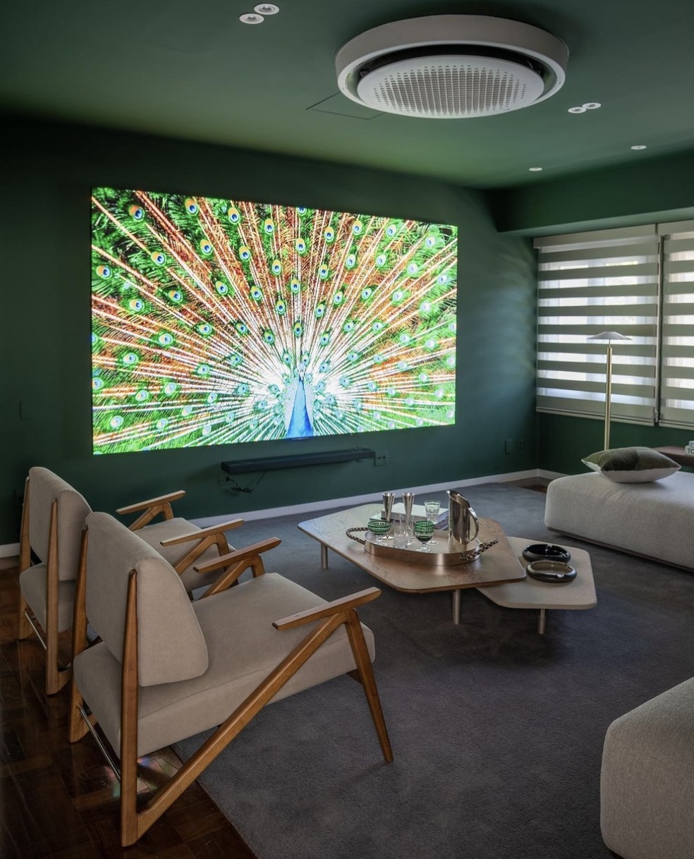 O tom verde nas paredes e no teto da sala de TV valoriza a percepção de qualidade de imagem — Foto: Cacá Bratke / Divulgação