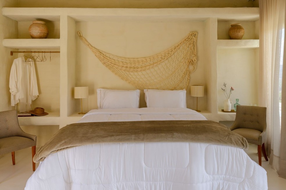 Suíte com nichos de reboco, decorada com objetos de viagem