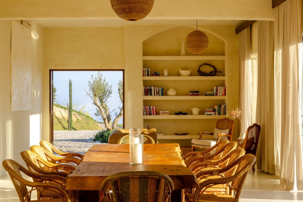 Sala de jantar com mobiliário de fibras naturais e estante de reboco rústico