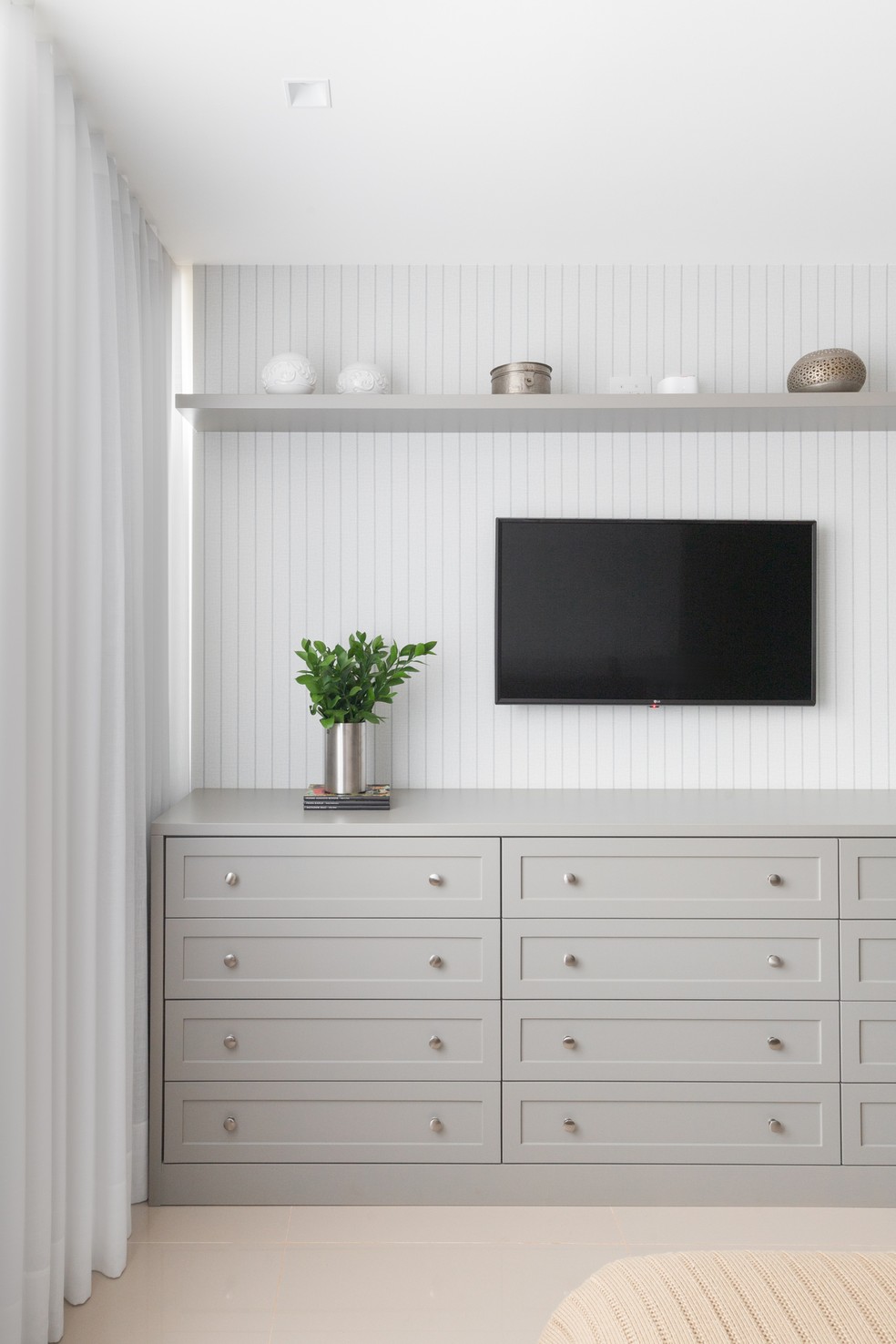 QUARTO DE CASAL | A TV do quarto está inserida na parede para seguir a ideia de poucos móveis e objetos também no ambiente de descanso — Foto: Júlia Tótoli / Divulgação