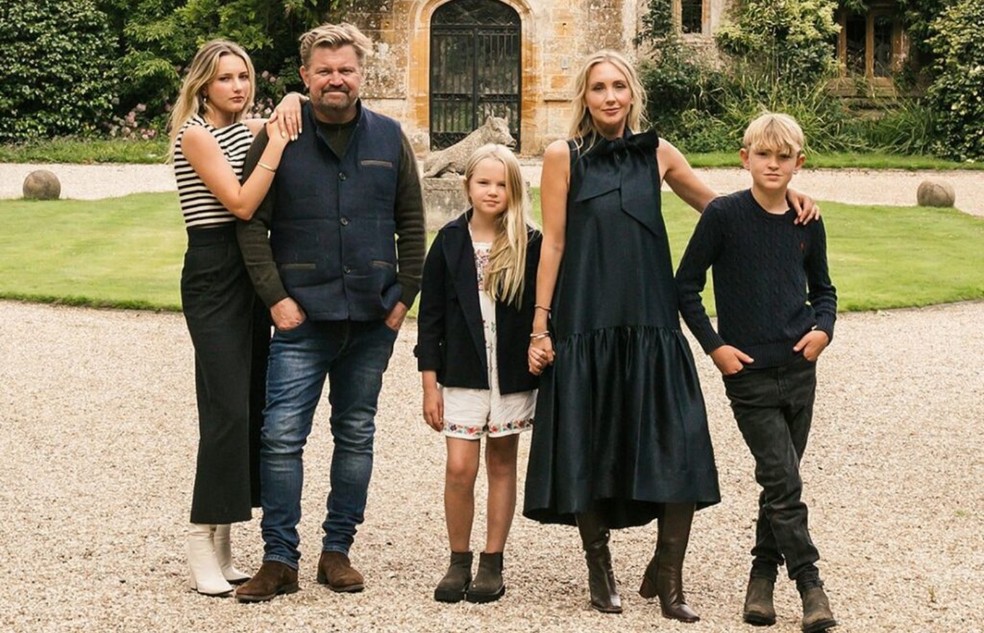 James Perkins e a esposa, Sophie, ao lado dos filhos em frente à Parnham House. O casal comprou a propriedade em 2020 e estima investir cerca de R$ 185 milhões para restaurar a mansão do século 16 — Foto: Divulgação