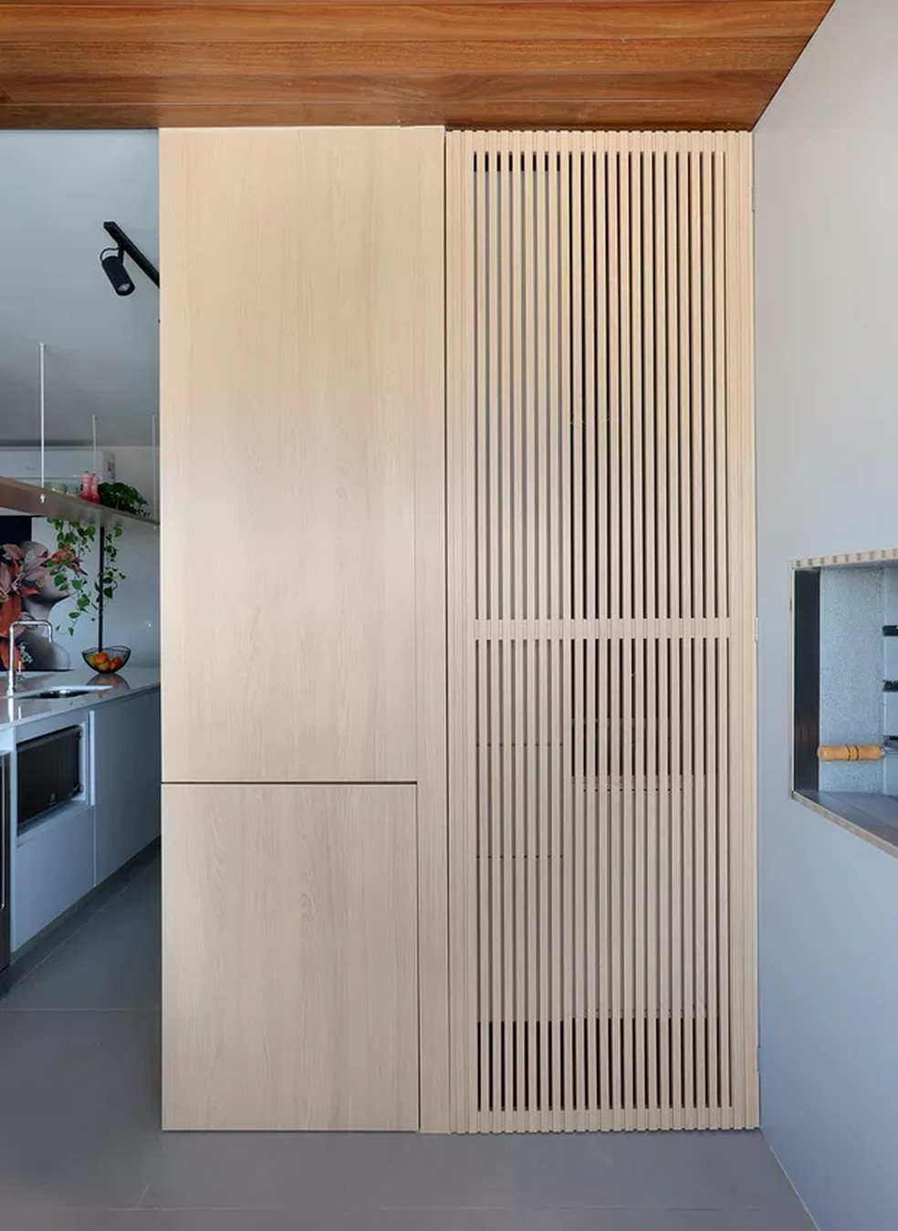 O escritório Studio92 desenhou uma porta de madeira ripada que mantém a linearidade entre os ambientes — Foto: Mariana Orsi / Divulgação