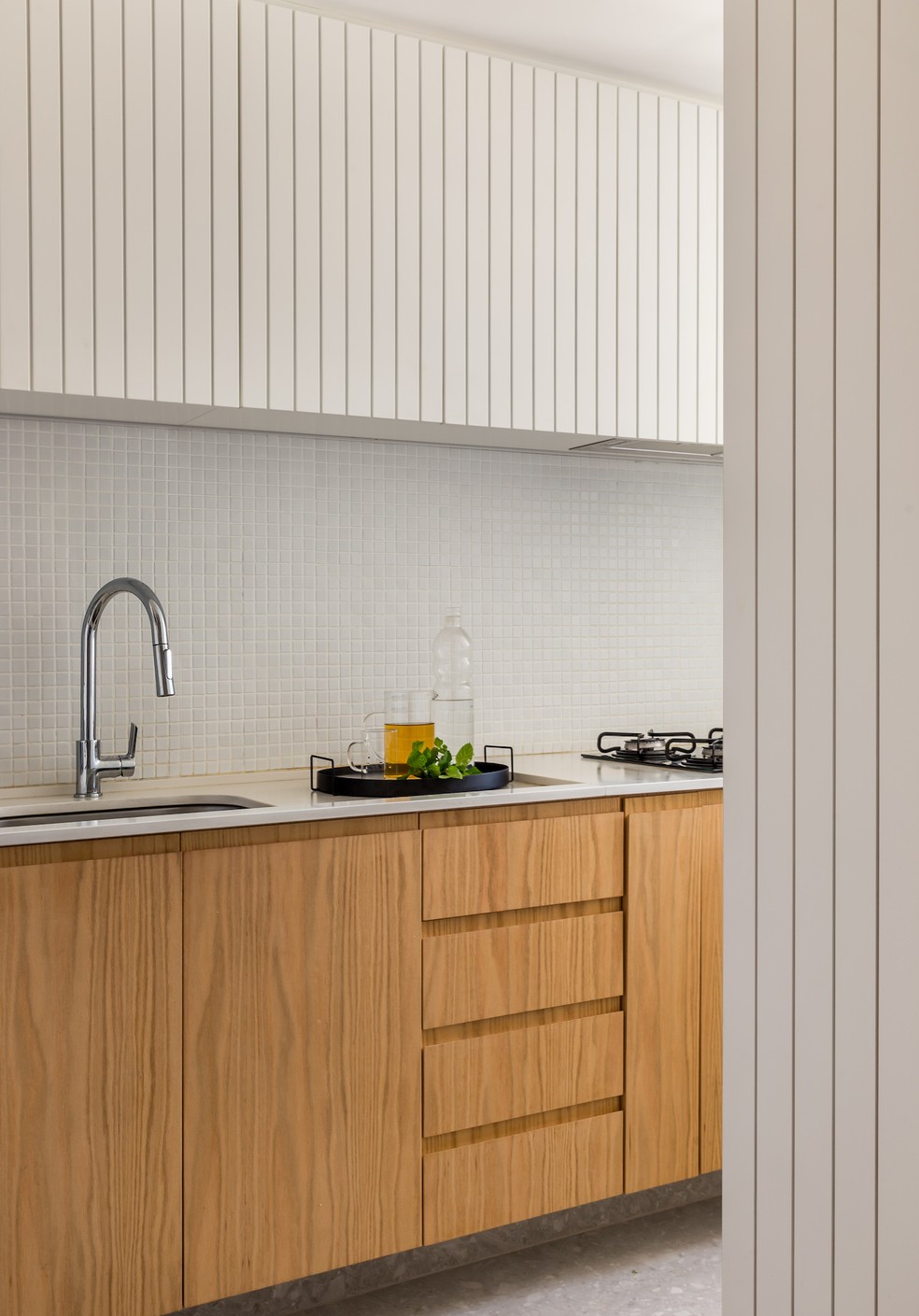 COZINHA | O uso do branco e da madeira conferem um ambiente intimista à cozinha, seguindo a proposta do pavimento inferior — Foto: Luiza Schreier / Divulgação | Produção: Andrea Britto