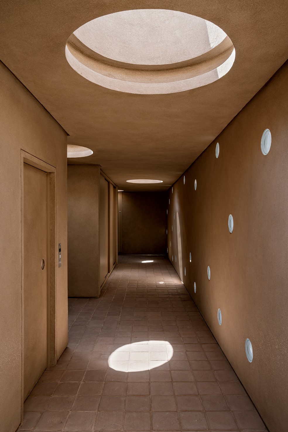 HALL | O hall de circulação da área íntima recebe iluminação natural de claraboias e tijolos redondos de vidro da Leroy Merlin — Foto: Fran Parente / Divulgação