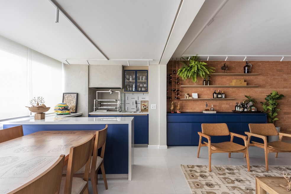 COZINHA | A marcenaria azul que vai da cozinha ao espaço gourmet, passando pela sala, foi executada pela Maricá Marcenaria — Foto: Thiago Travesso / Divulgação