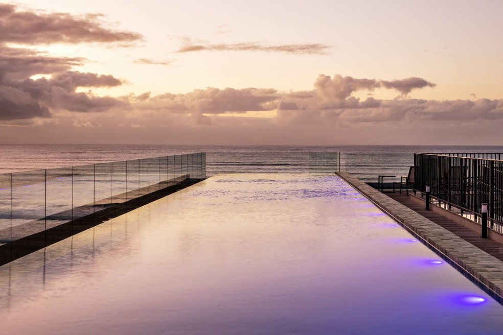 A piscina de borda infinita e guarda-corpo de vidro tem vista para o mar — Foto: Nelson Kon / Divulgação