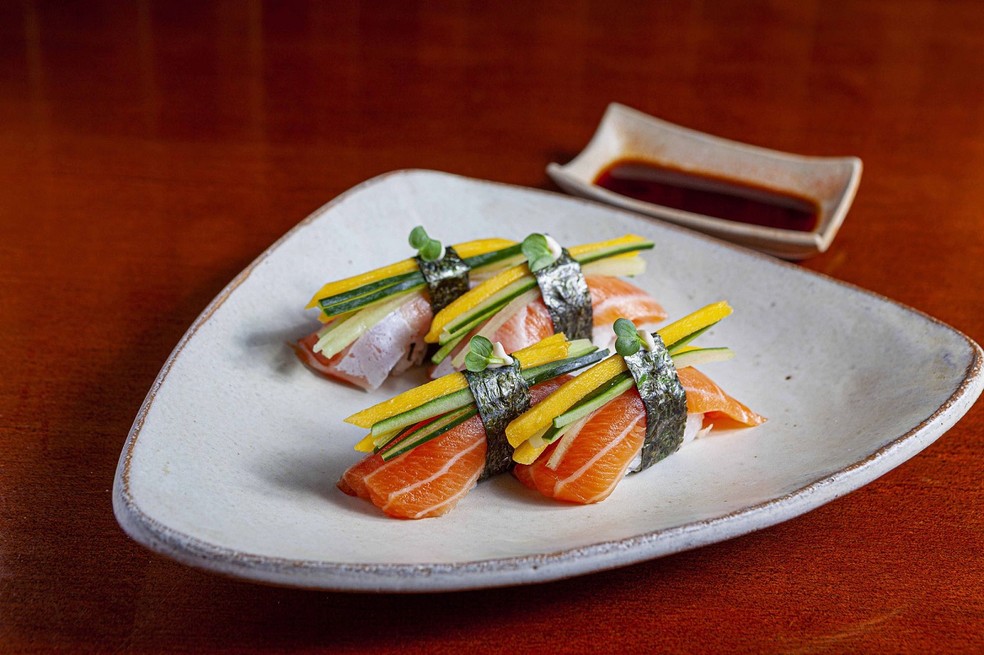 Fixe os filetes de manga e pepino no niguiri de barriga de salmão com uma folha de nori — Foto: Daiki Sushi / Divulgação