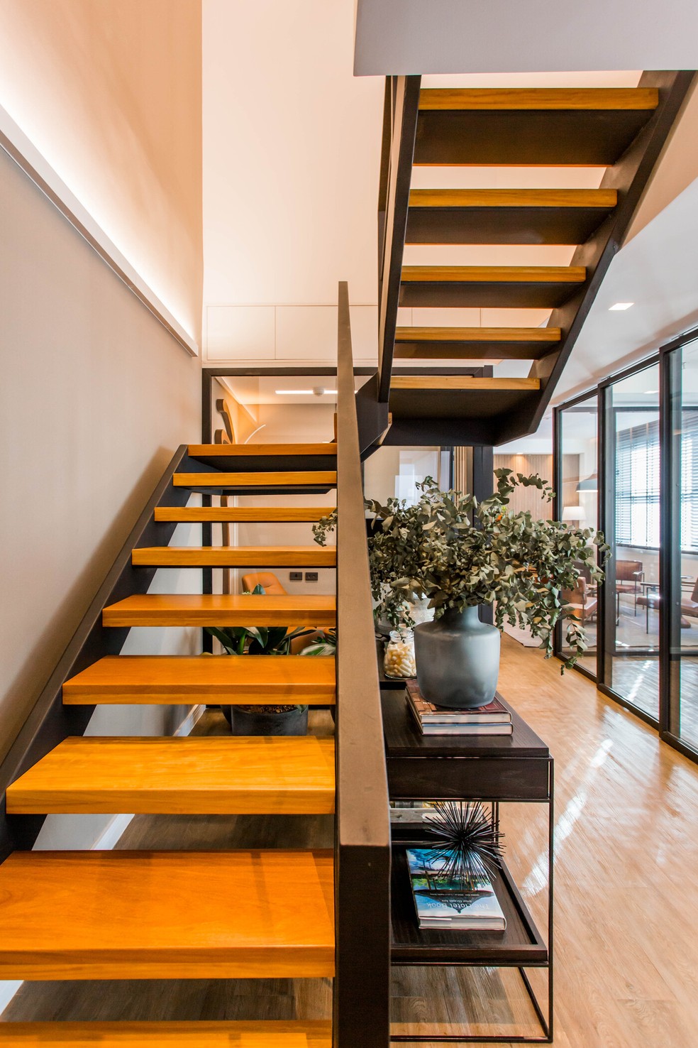 Um aparador com plantas e decorações é ideia do que fazer com espaços abaixo de escadas. Projeto de KAS ARQ e Daniela Garcia — Foto: Dicastanha / Divulgação