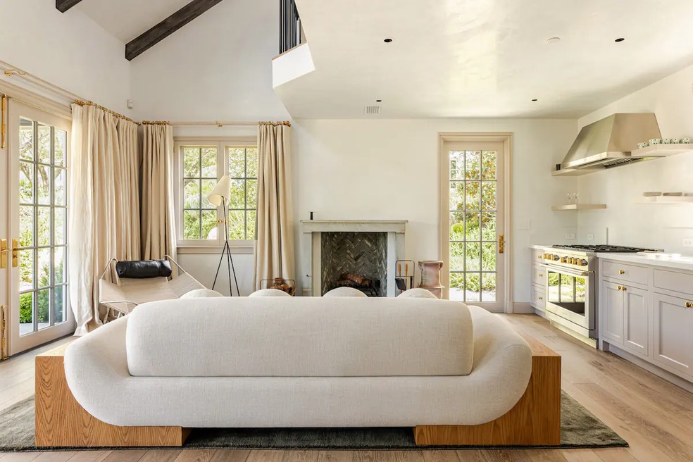 A sala de estar tem lareira e é integrada com a cozinha — Foto: Airbnb / Reprodução