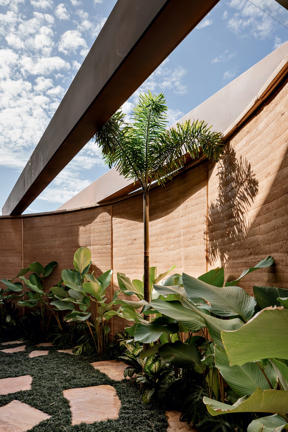 JARDIM | O jardim interno ocupa as pontas das paredes curvas de taipa. Obra concluída em 2023 pela construtora Lampur — Foto: Fran Parente / Divulgação