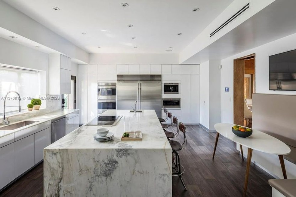 A cozinha tem uma bancada grande de mármore com espaço para refeições em família — Foto: Realtor.com/Reprodução