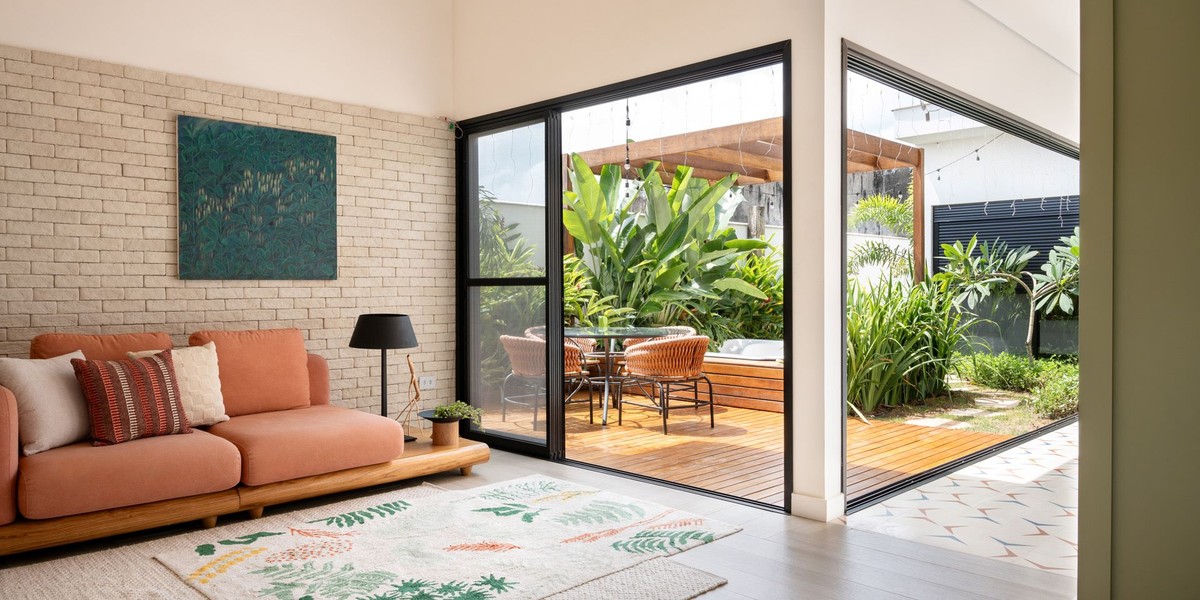 Casa minimalista tem pontos de cor e integração com jardim e piscina