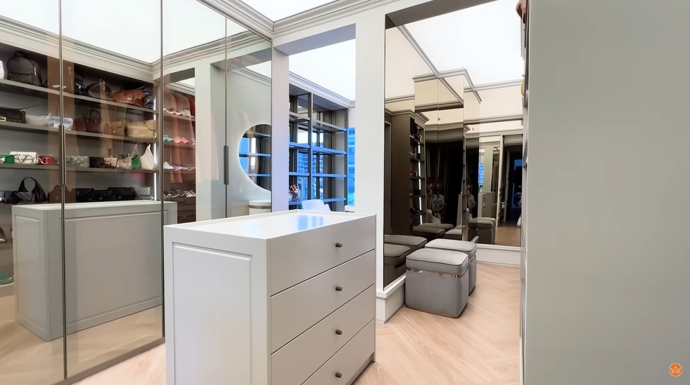 O closet tem diversos espelhos e o móvel no centro guarda acessórios. O espaço inclui ainda a penteadeira. — Foto: Youtube / Reprodução