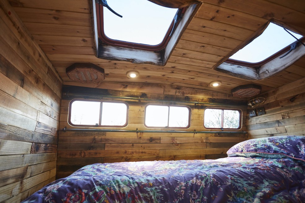 O mezanino tem janelas, claraboias e um colchão de casal na casa feita em um caminhão de cavalos — Foto: House Box / Reprodução
