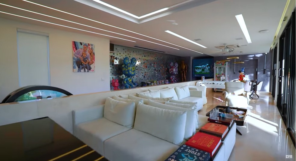 A sala espaçosa de Luccas Neto tem diversos sofás e uma pista de boliche — Foto: Youtube / Reprodução