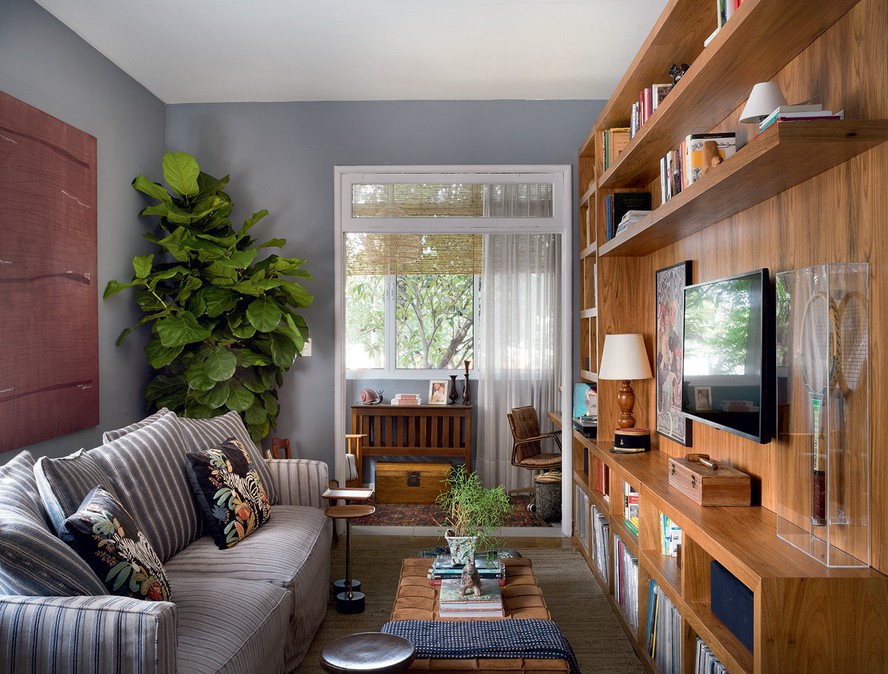 SALA | A estante sob medida em linhas retas, executada com folha natural de freijó, guarda a coleção de vinis de André. Tapete da By Kamy