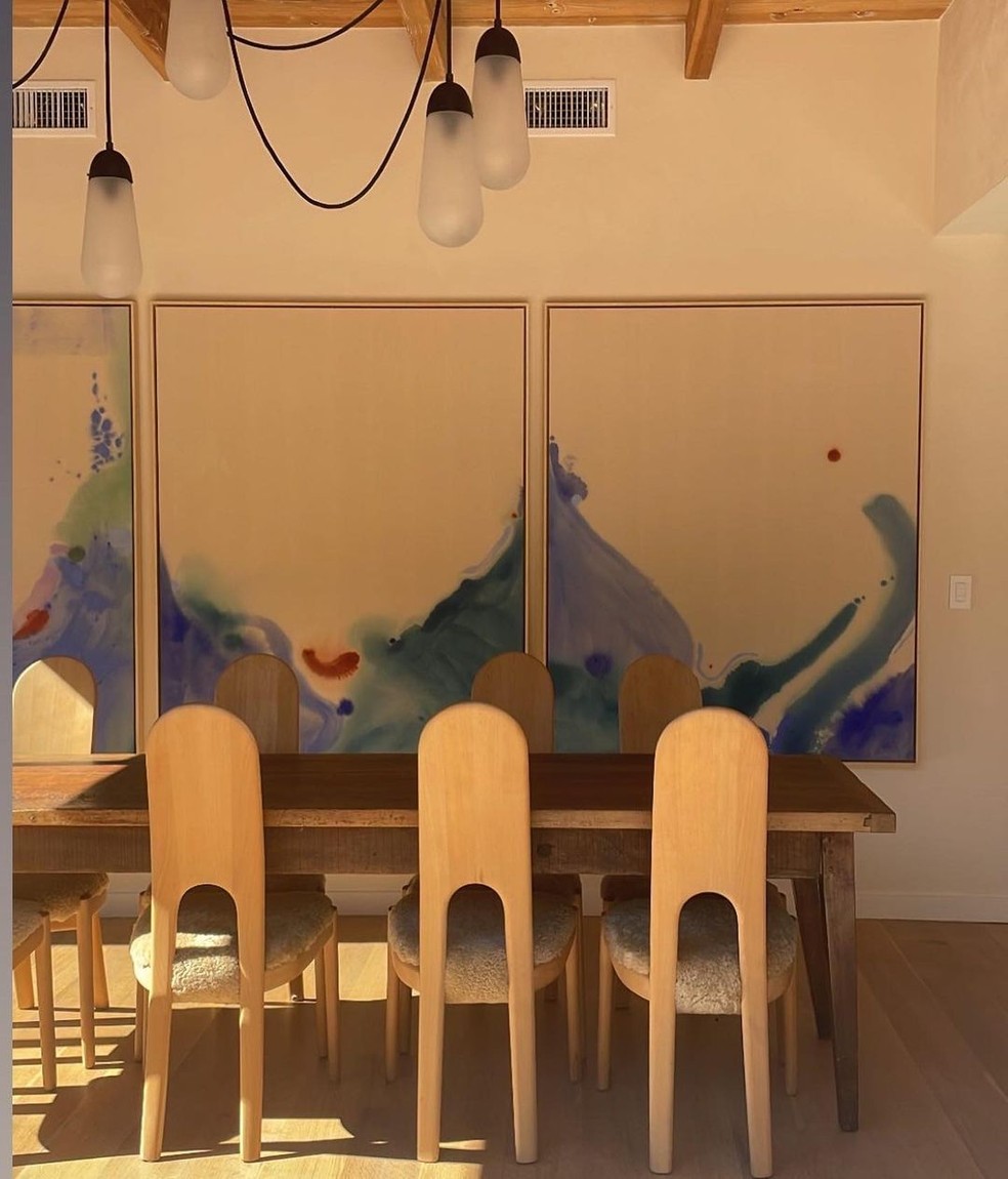 A sala de jantar tem uma mesa de madeira e quadros grandes nas paredes — Foto: Instagram / Reprodução