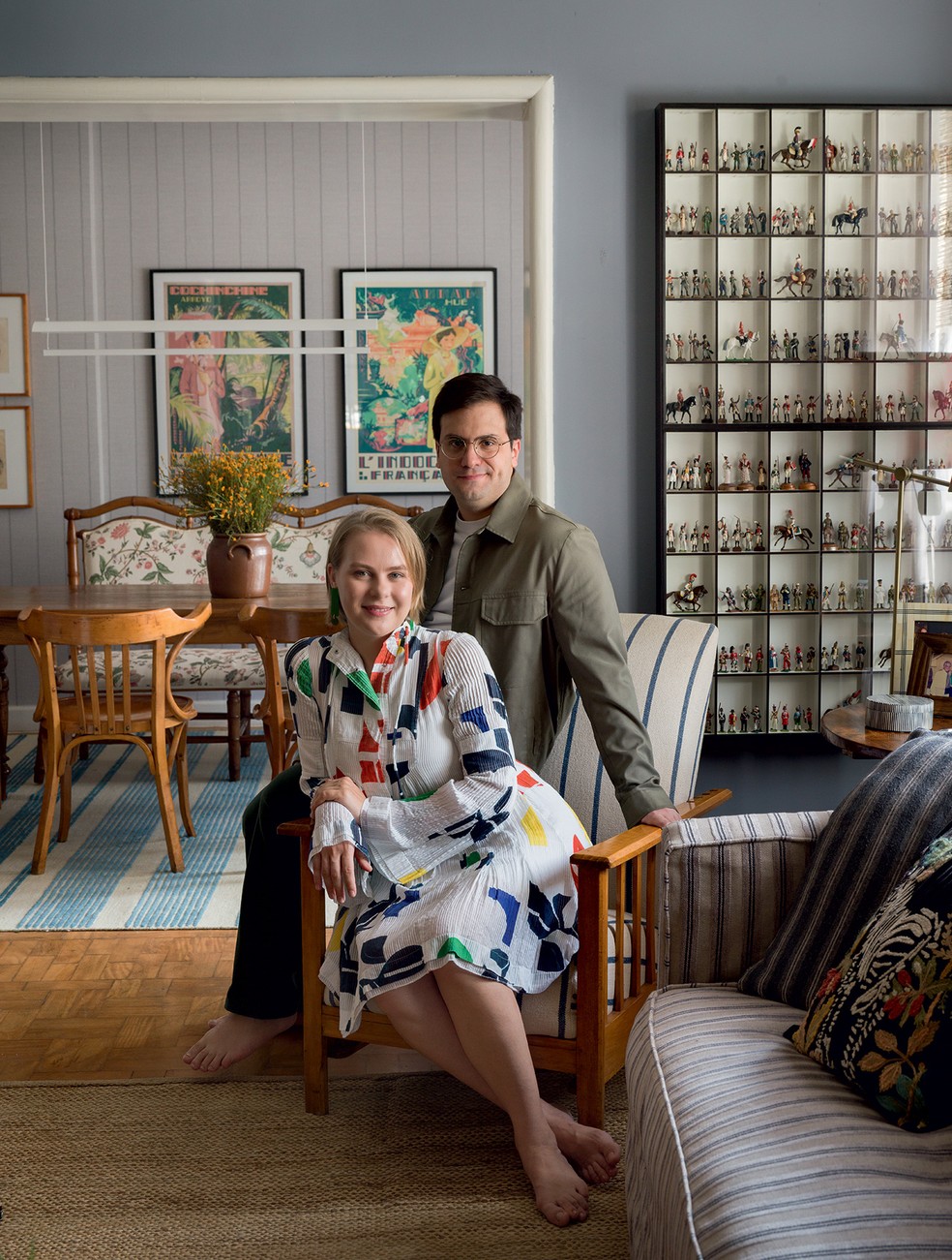 RETRATO | André Danemberg e Anastasiia Lytvynenko estão na sala, tendo ao fundo a coleção de soldadinhos de chumbo que ele herdou do avô, com peças que representam diversas partes do mundo — Foto: Romulo Fialdini/Divulgação