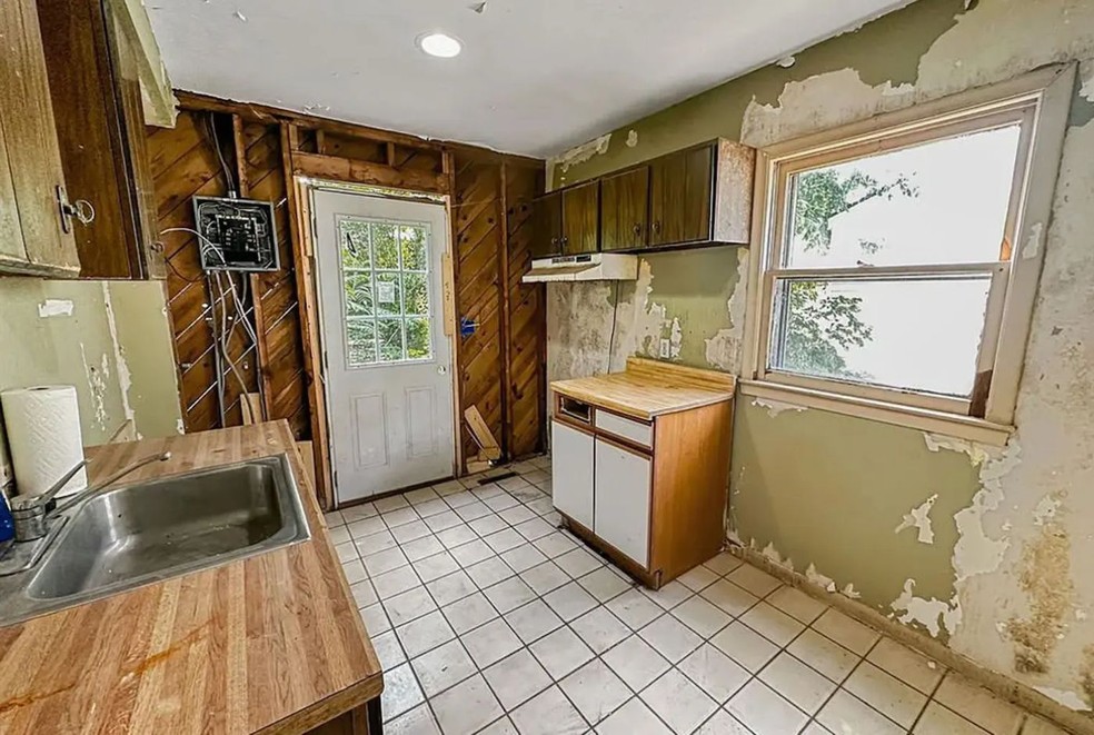 A cozinha está bastante deteriorada, com mofo e fiações expostas — Foto: Good Company Realty / Reprodução