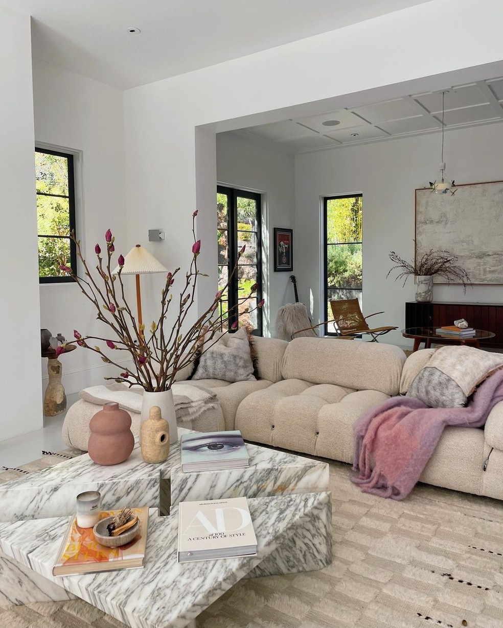 A sala de estar tem um sofá branco grande e uma mesa de mármore — Foto: Instagram / Reprodução
