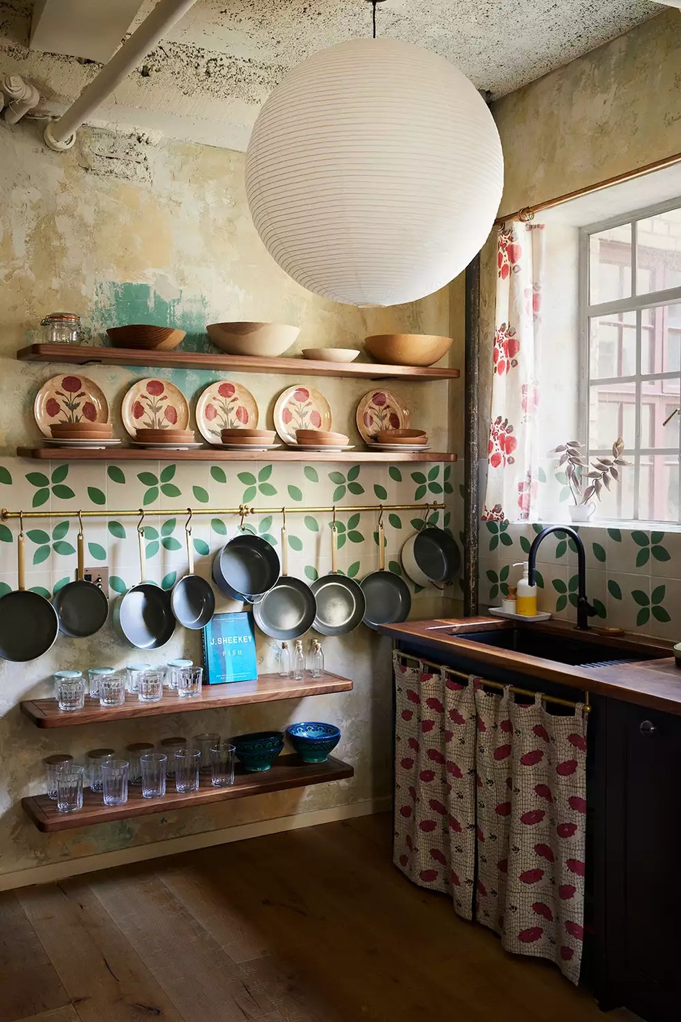 A cozinha tem uma papel de parede floral e prateleiras com itens pendurados — Foto: WINNIE AU / Reprodução