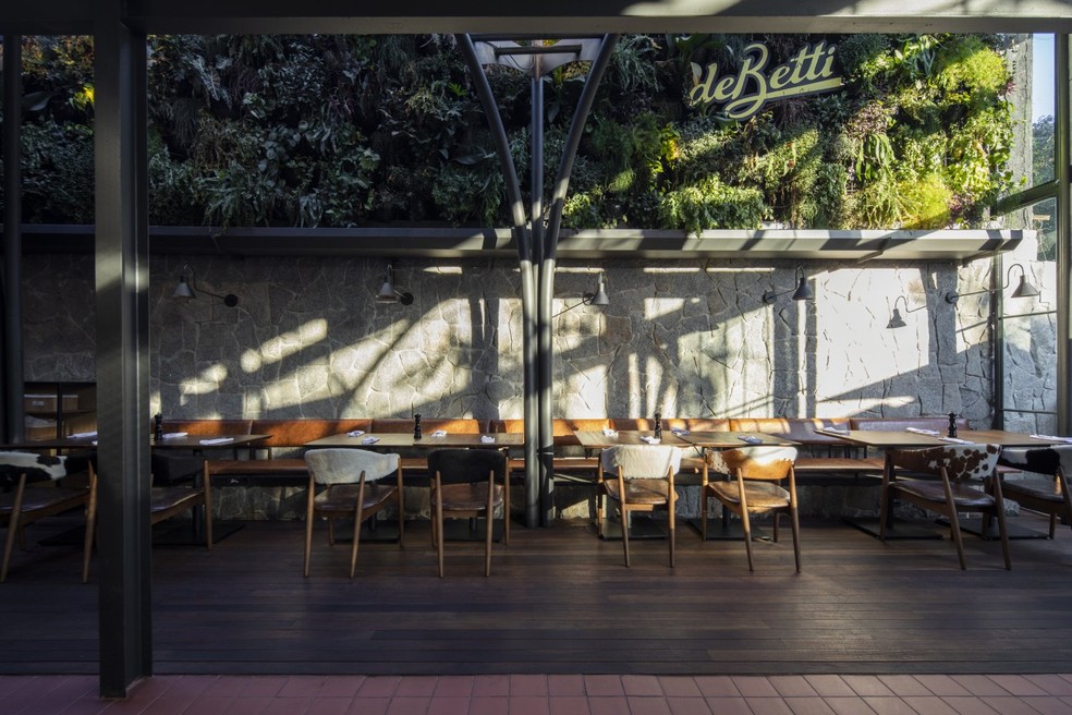 Um jardim vertical foi posicionado no fundo do restaurante para imprimir uma sensação de acolhimento no espaço — Foto: Maíra Acayaba / Divulgação